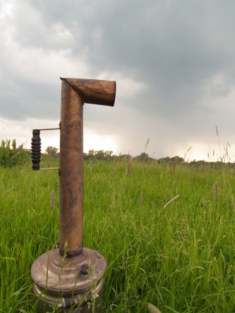 Russian teapot (samovar) in green field under rainy skyの写真素材