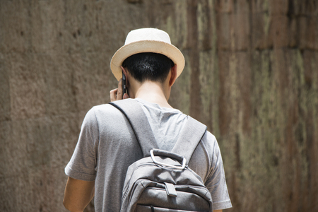 Man in hat with a bag holding mobile phone.の写真素材