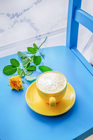 Coffee with coconut milk and yellow rose on a blue backgroundの写真素材