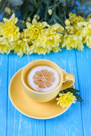 Lemon tea and yellow chrysanthemums on a blue wooden background. Free spaceの写真素材