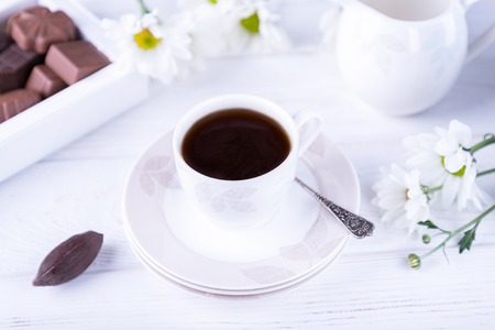 Porcelain cup of black coffee and chrysanthemums flowers on a white wooden backgroundの写真素材