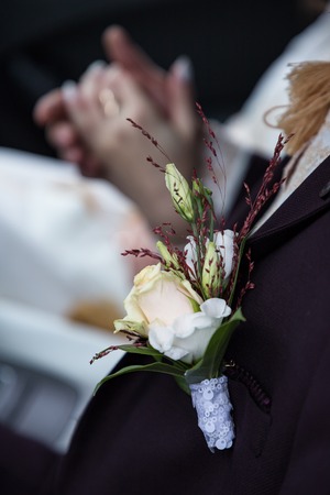 Beautiful groom boutonniere or buttonhole on a background of deep purple suit. Close upの写真素材