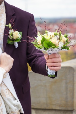 Ivory and green wedding bouquet of roses and carnation flowers in the hand of the groom. Wedding conceptの写真素材