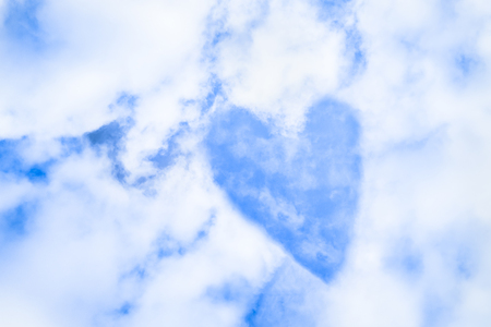 A heart in the blue sky with white fluffy cloudsの写真素材