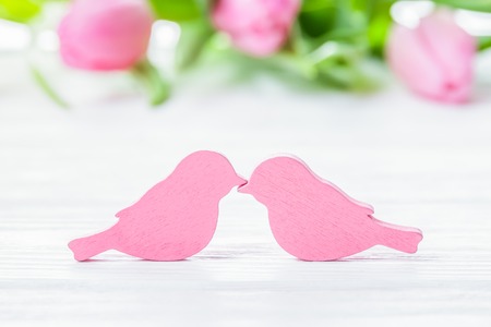Two pink birds kissing on the pink tulips backgroundの写真素材
