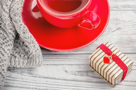 Red cup of tea, knitted mitts and a gift for Valentine's Day on a gray wooden backgroundの写真素材
