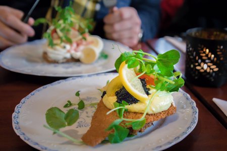 Delicious traditional danish open sanwiches smorrebrod with dark rye bread, fried fish, black caviar, lemon and green sproutsの写真素材
