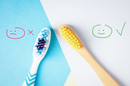 Plastic and bamboo toothbrushes on blue and white background. Alternative concept. Minimalism....