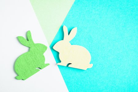 Happy Easter. Yellow and green wooden Easter bunny on colored geometric background. Trendy creative...
