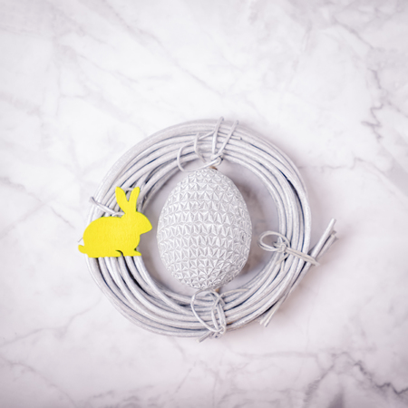 Silver easter egg and yellow easter bunny in the nest on the marble background. Minimal concept, copy spaceの写真素材