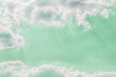 Delicate light rays through clouds on a pastel green color sky background. Copy space