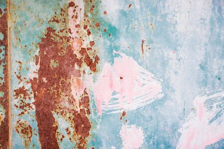 Rusty metal surface with pink, green, blue, turquoise paint flaking. Old cracked paint pattern,...