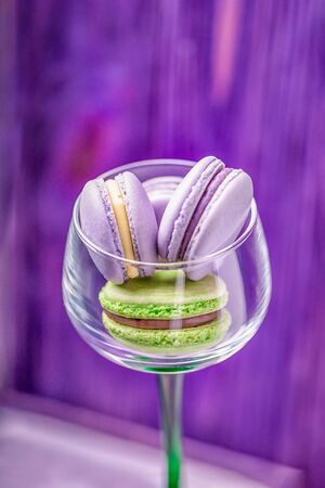 Homemade traditional french violet and green macaroons in a glass on purple background. Copy spaceの写真素材