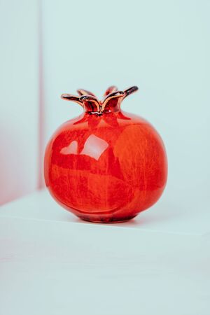 Red ceramic vase pomegranate fruit on a white pink background. Copy space, toned photoの写真素材