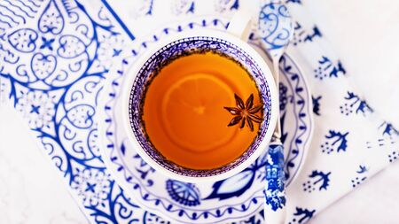 A cup of lemon tea with anise star, white and blue dishes. Copy space. 16 on 9 panoramic format