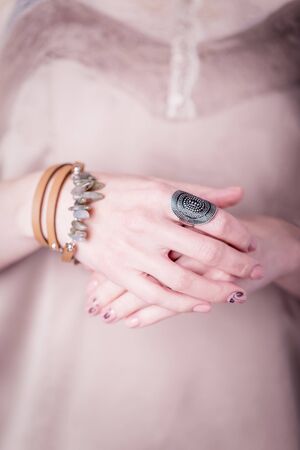 Beautiful female hands on a light beige silk background. Manicure with pink color nail polish, black floral patternの写真素材