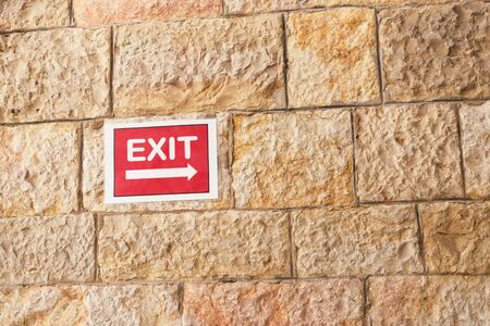 Red exit sign on sandstone wall background