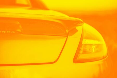 Fashionable sports yellow orange gradient color car. Fragment, details. Yellow toned photo. Copy...