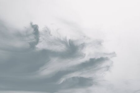 Dramatic gray clouds like paint strokes in the light sky. Wind and sky. Copy space