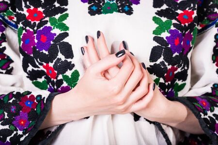 Woman in an old Ukrainian embroidered shirt, fragment. Manicure with black nail polishの写真素材