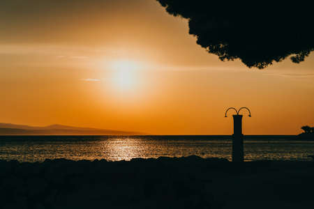 Amazing sunset seascape. Beach shower and orange sky. Brela, Croatia, Makarska rivieraの写真素材
