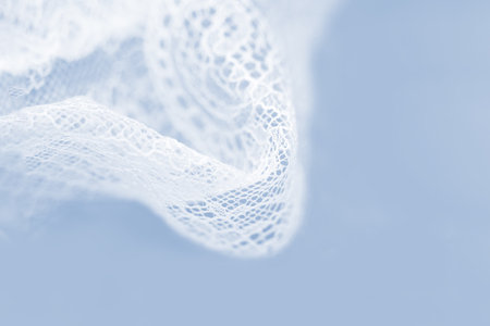 Delicate white silk lace lingerie, light blue background, copy space