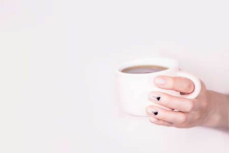 Female hand holding pink cup of black tea on pale pink background, copy spaceの写真素材