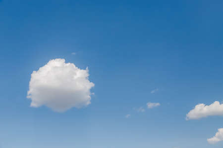 Fluffy white small clouds on a bright clear blue skyの写真素材