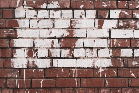 Abstract grunge background. Old brick wall stained with paint. White paint with smudges on red brick.の写真素材