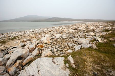 The rocky shore of the lake in the steppe. A lot of stones. The whole coast is in stones. Hills in the background. Copy space.の写真素材