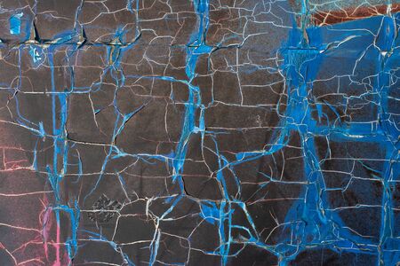 Abstract grunge background. The texture of the torn old tattered paper on the wall looks like dry ground in the steppe. Blue, red, black color.の写真素材