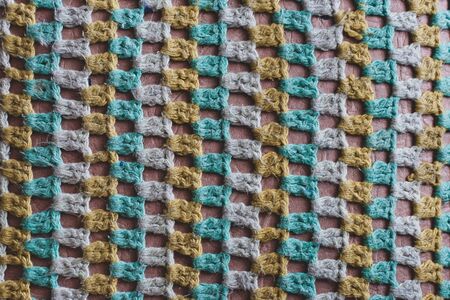 Old woolen knitted fabric in a mesh. Green, white, yellow threads. Deep hole texture. Knitted cover on a chair.の写真素材