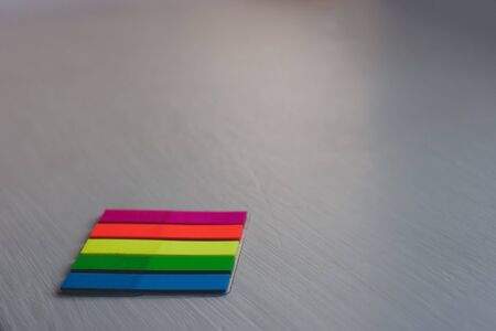 A set of colored bookmarks lies on a light colored surface from the bottom left. Stripe stickers. Red, yellow, green, blue. Selective focus, blurred background. Copy space.の写真素材