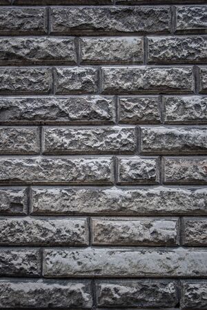 Textural background of natural stone laid in the wall. Grey colour. Vertical frame.