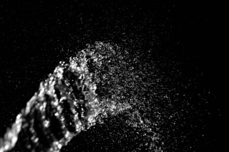 Sparkling water jet with splashes on a dark background. Selective shallow focus. Motion blur.の写真素材