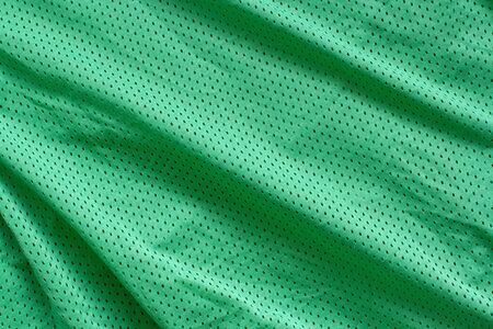 Fabric texture. Green fabric with folds. Roughnesses and waves on the surface.