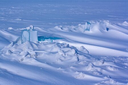 Carved large pieces of ice in snow hummocks on Lake Baikal. Winter landscape. The ice is covered...