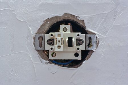 An electric switch with one button with the cover removed is recessed into the putty wall. Stages of...