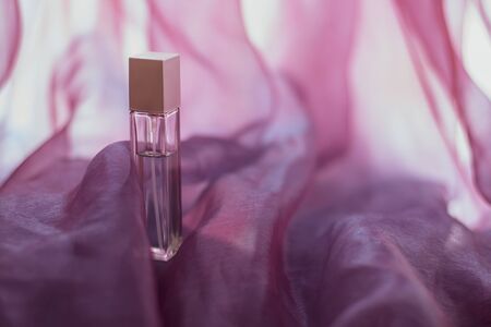 An elongated perfume bottle with pink airy fabric. Faceted glass vial.  Wavy light fabric with...