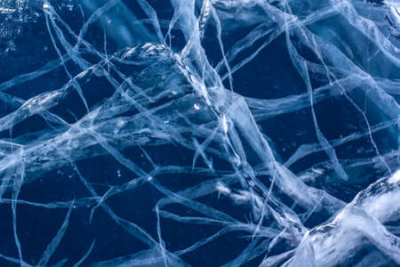 Strips of cracks in the clear blue ice. Beautiful patterns. Horizontal.の写真素材