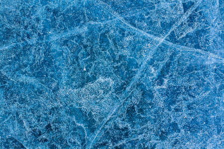 Unique background texture of ice. Winter pattern on the blue ice of the lake. Cracks and air bubbles. Horizontal.の写真素材