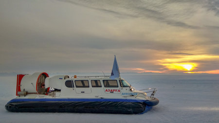 Listvyanka, Russia - February 29, 2020: A hovercraft stands on the ice of Lake Baikal at sunset. Khivus in the snow with beautiful sky and clouds. Mobile photo. Horizontal.のeditorial素材