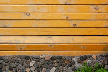 Background of worn lining boards with many knots and row of stacked stones below. Horizontal image.の写真素材