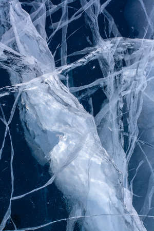 A large crack in the ice with small cracks around. Blue transparent ice.