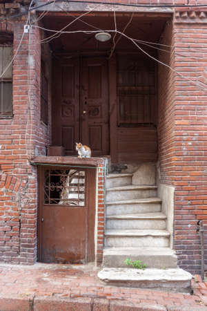 Old door in brick house with worn out concrete staircase and an entrance to basement. Lots of wires.の写真素材