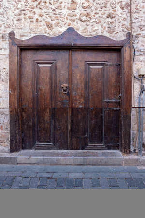 Old shabby wooden door with forged door knocker and doorknob.の写真素材
