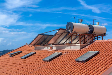 Solar water heater installed on roof of house for cheap water heating.の写真素材
