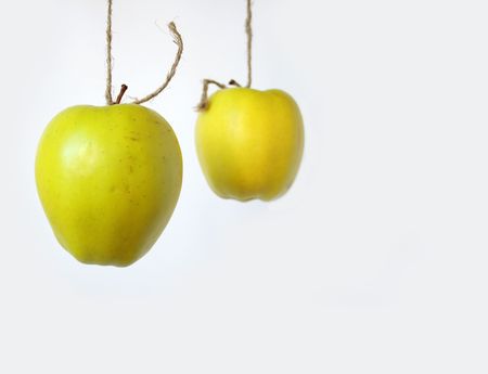 Two green apples hanging on cord on white backgroundの写真素材