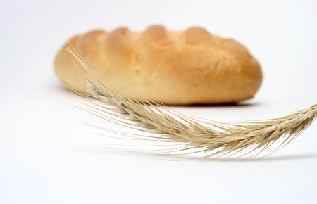 Close-up at wheat ear on background with white bread stickの写真素材