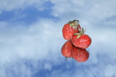Two nice red strawberry with reverberation lying on blue sky backgroundの写真素材